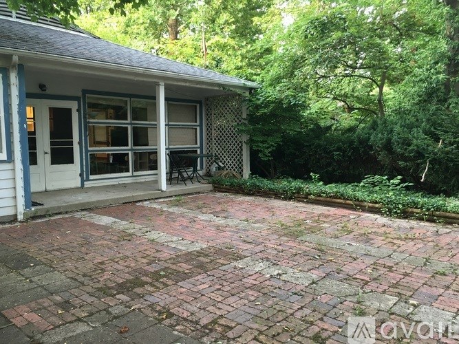 A house with a brick patio surrounded by trees.