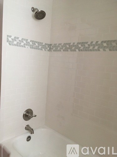 A white bathtub with a silver faucet and a silver shower head.