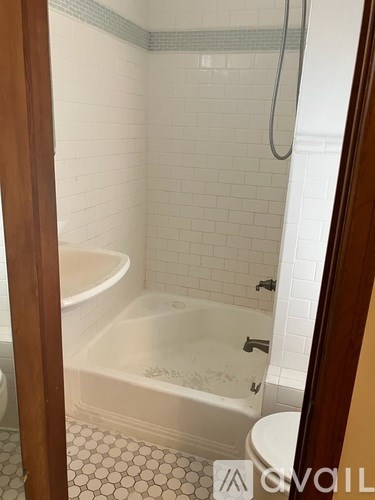 A white tiled bathroom with a bathtub and toilet.