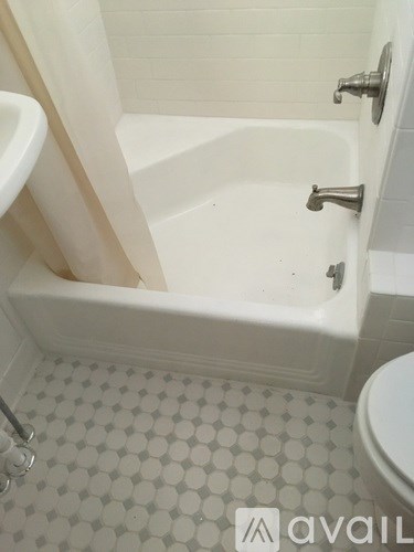 A white bathroom with a tub, toilet and sink.