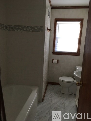 A bathroom with a toilet, tub, and window.