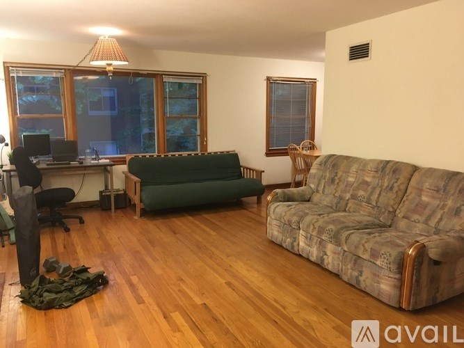 A room with a green couch and a wooden floor.