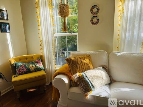 A living room with a yellow chair and a white couch.