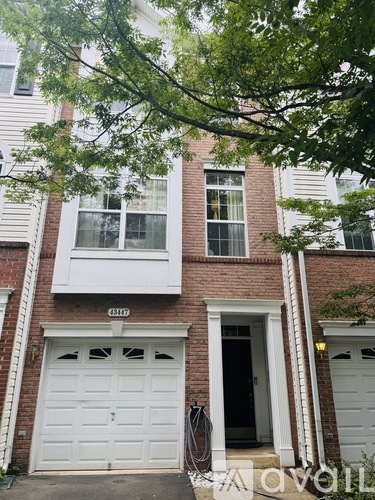 A white garage door is on the left side of a brick building.