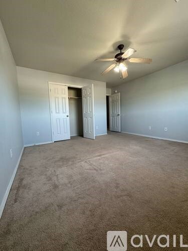 A room with a carpeted floor and a ceiling fan.