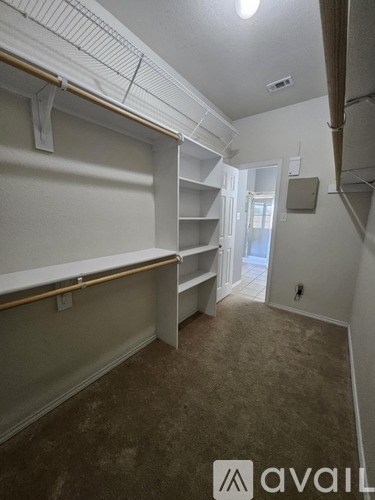 Empty room with shelves and a doorway leading to another room.