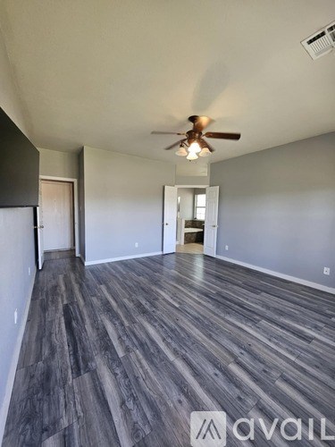 A room with a ceiling fan and wooden flooring.