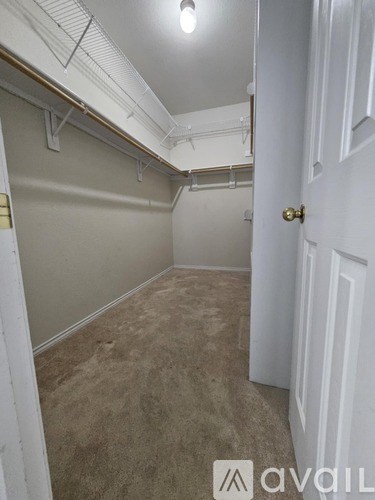 A room with a white door and a carpeted floor.