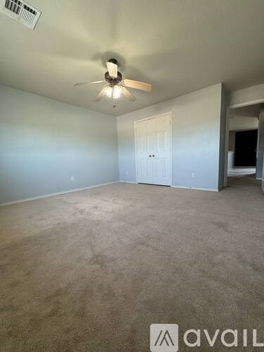 A room with a ceiling fan and carpeted floor.