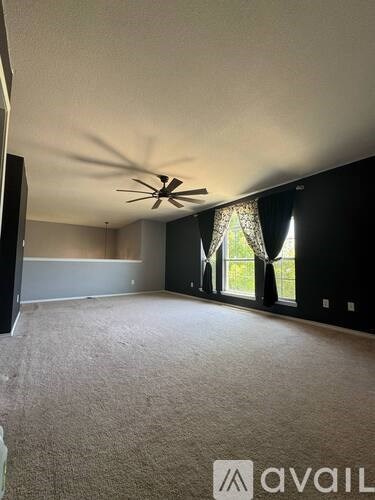 A room with a ceiling fan and carpeted floor.