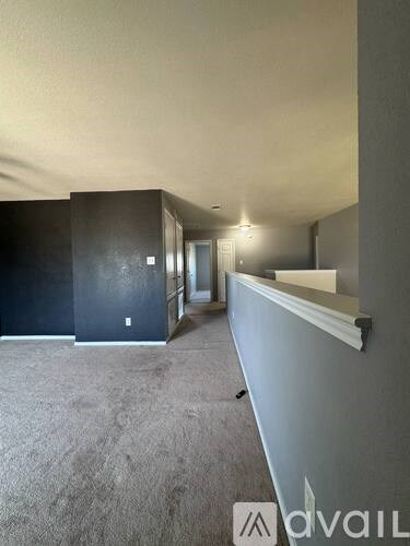 A carpeted hallway with a wall on the right side and a doorway in the distance.