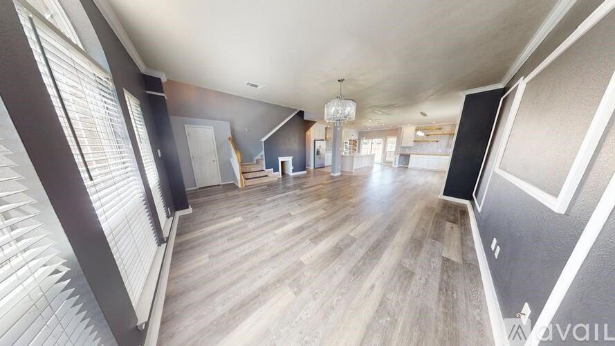 A large open room with wooden floors and a staircase with a wooden railing.