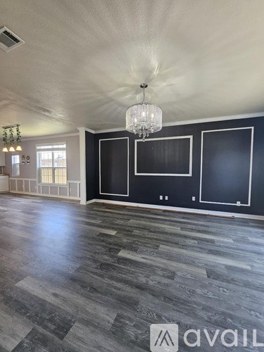 A room with a grey floor and a chandelier hanging from the ceiling.