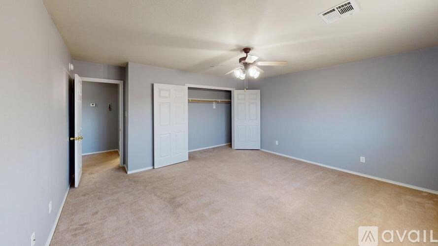A spacious room with a ceiling fan and two doors.