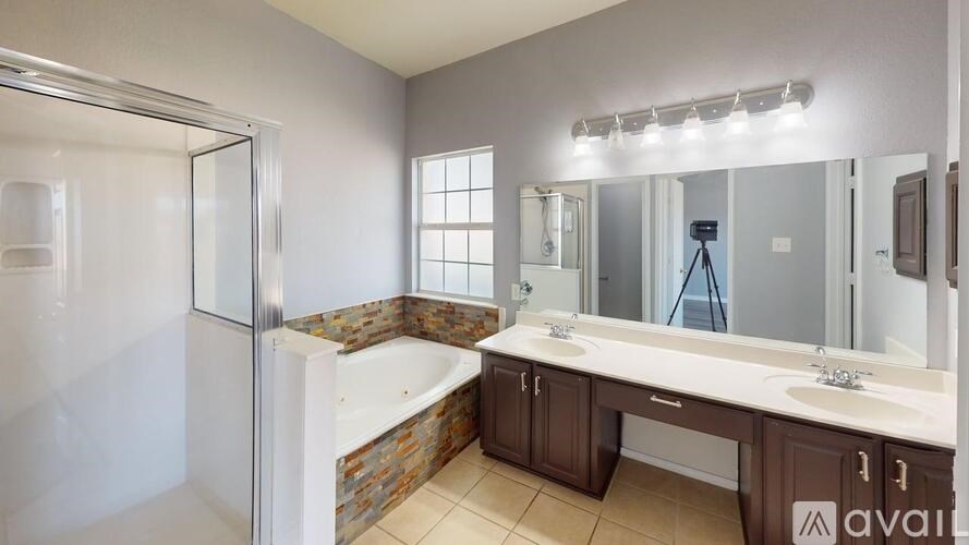 A bathroom with a tub, sink, and mirror.