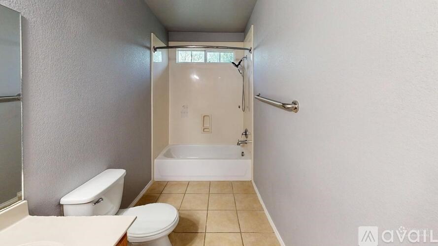 A white toilet sits next to a white bathtub in a small bathroom.