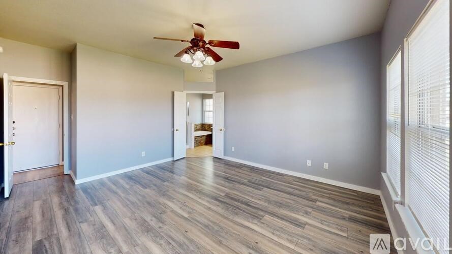 A room with a ceiling fan and wooden flooring.