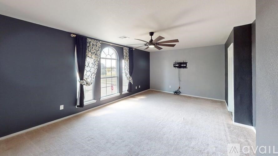 A spacious room with a ceiling fan and a large window.