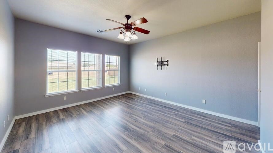 A room with a ceiling fan and wooden flooring.