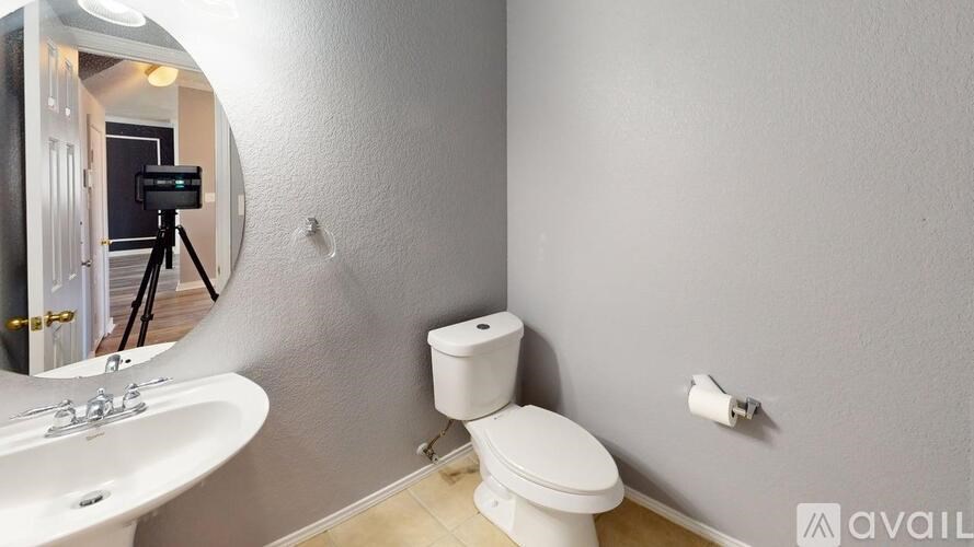 A bathroom with a toilet, sink, and mirror.