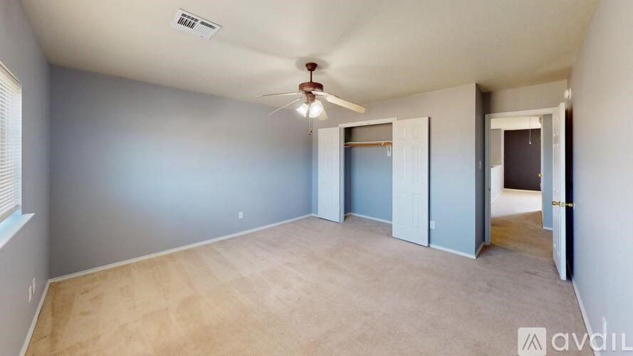 A room with a ceiling fan and light fixture, and a doorway leading to another room.
