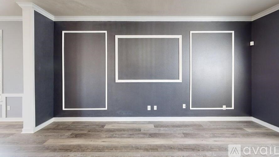 A room with a grey wall and a wooden floor.