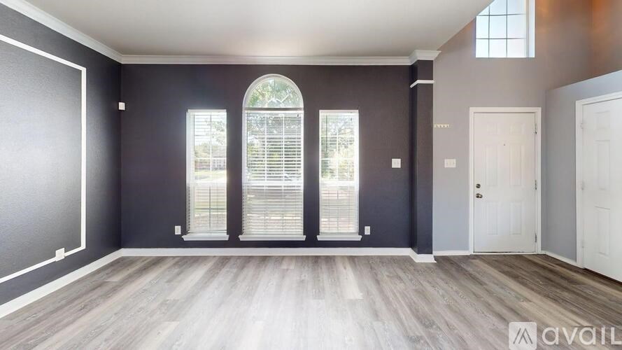 A room with a large arched window and wooden flooring.