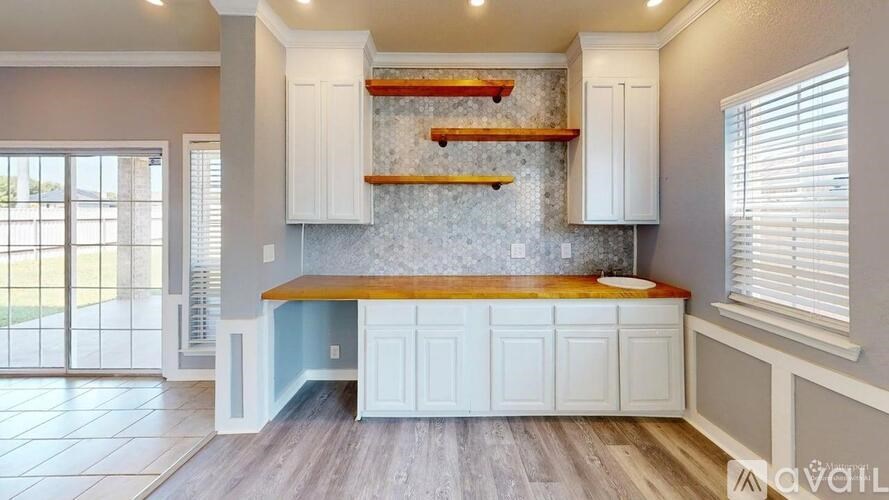 A kitchen with white cabinets and a wooden island.