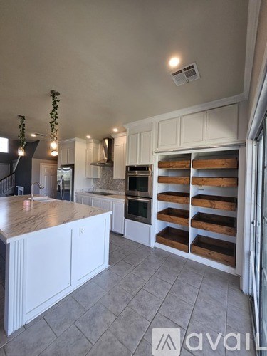 A kitchen with white cabinets and a marble countertop.
