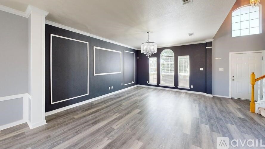 A spacious room with wooden flooring and a chandelier.