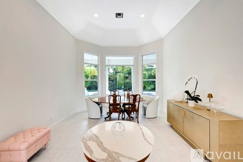 A modern living room with a large window and a dining table set up.
