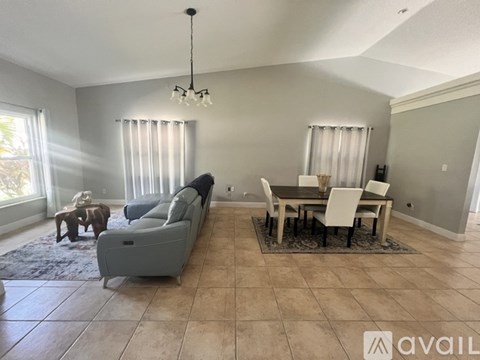 A living room with a grey couch, a wooden coffee table, and a dining table with chairs.