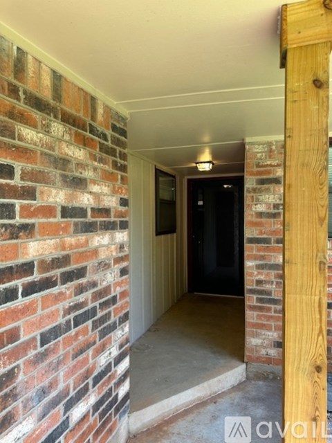 A hallway with a brick wall and a door.