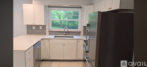 A kitchen with white cabinets and a black refrigerator.