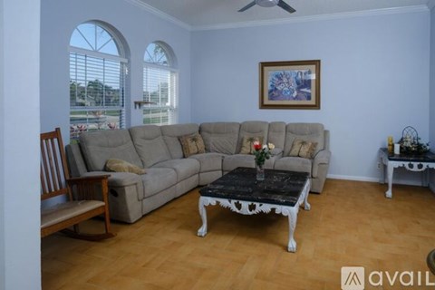 A living room with a grey sectional sofa, a black and white coffee table, and a painting on the wall.