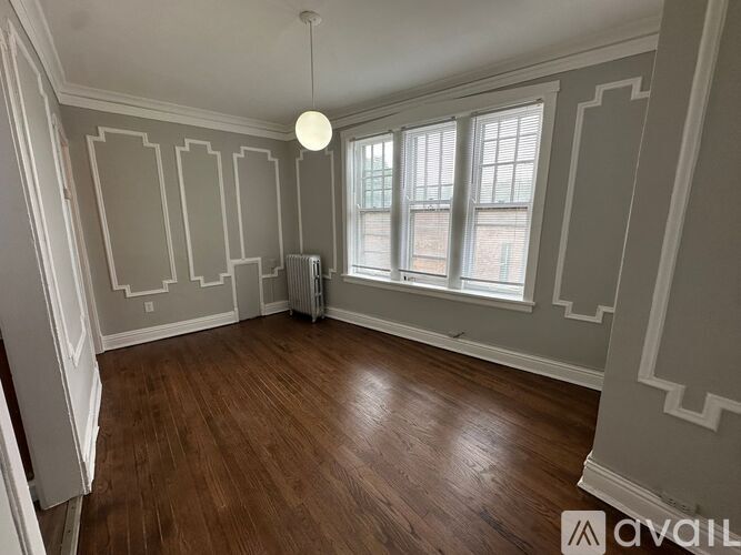 A room with wooden floors and a window with a view of a building outside.