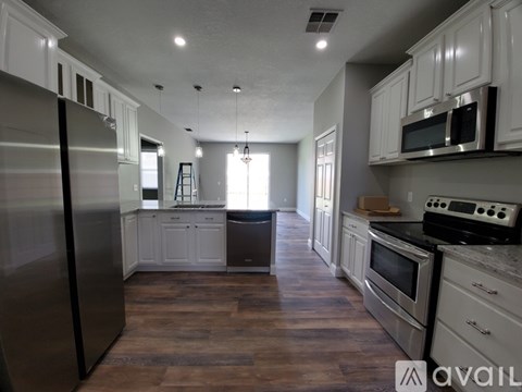 A kitchen with white cabinets and a wooden floor.