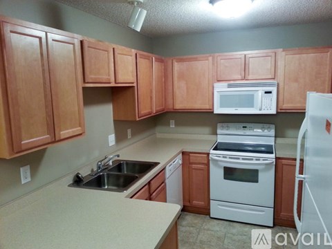 A kitchen with brown cabinets and white appliances.
