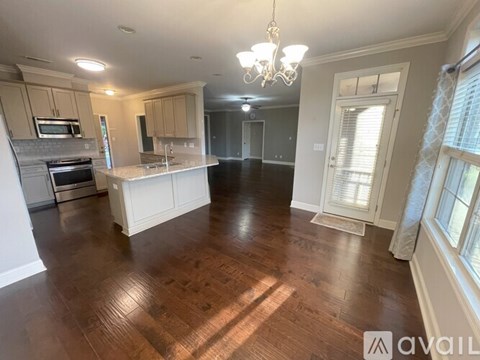 A large open living space with wood flooring and a kitchen area.