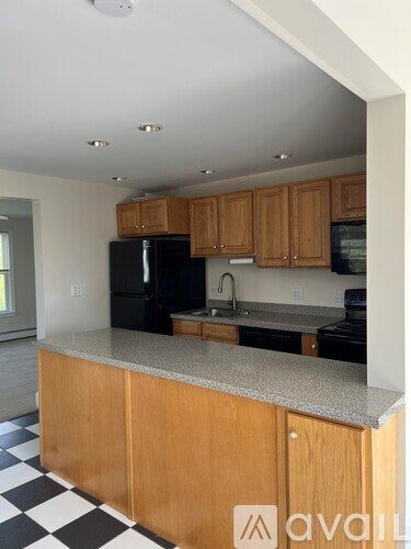 A kitchen with black appliances and wooden cabinets.