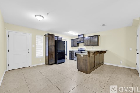 A kitchen area with a wooden island and a black refrigerator.