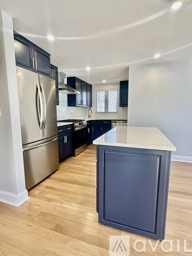 A kitchen with a stainless steel refrigerator and wooden flooring.