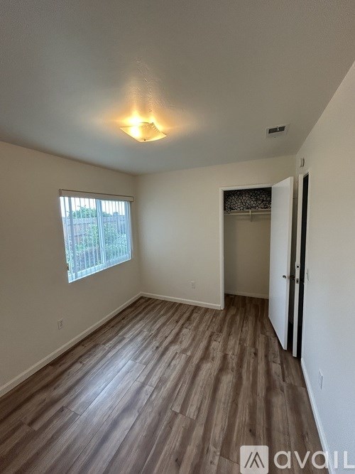 A room with wooden flooring and a window with blinds.