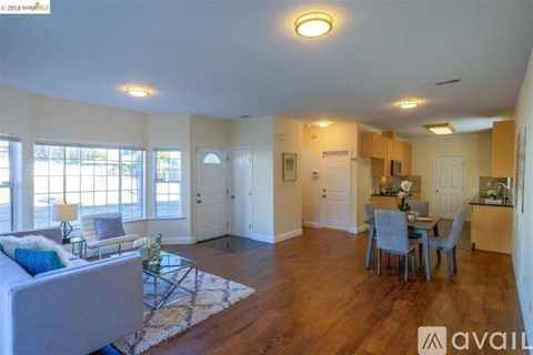 A living room with a white couch and a dining table with chairs.