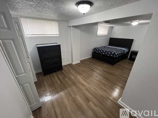 A bedroom with a bed, dresser, and a ceiling light.