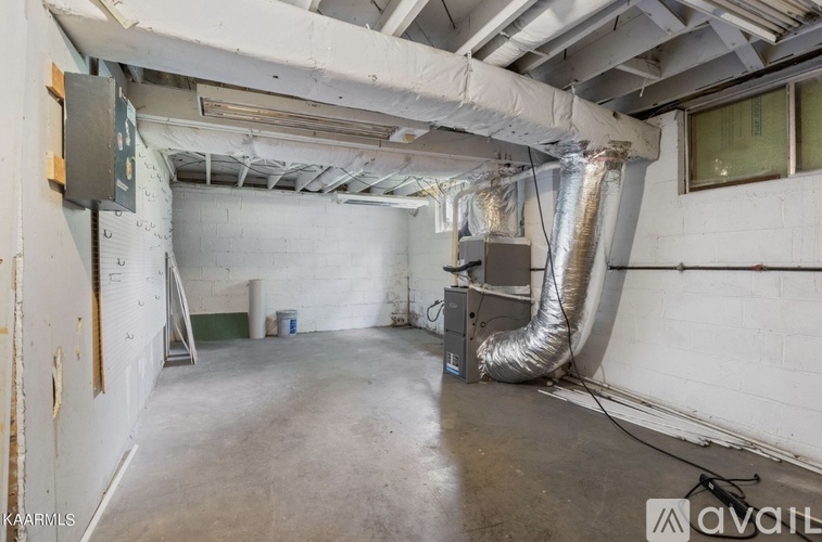 A large, empty industrial space with a metal pipe running along the wall.