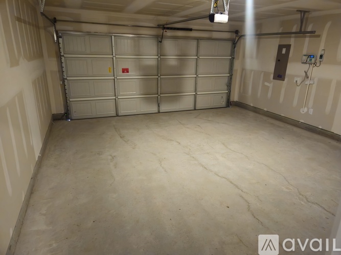 A spacious garage with a closed metal door and a fire extinguisher on the wall.