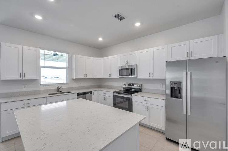 A modern kitchen with white cabinets and appliances.
