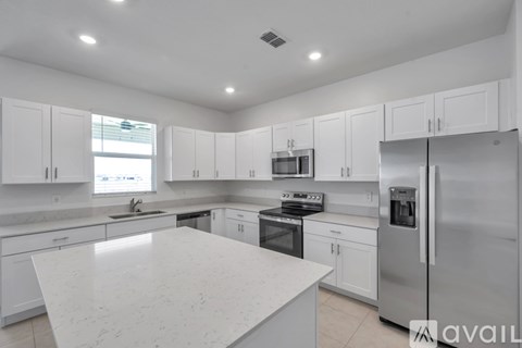 A modern kitchen with white cabinets and appliances.