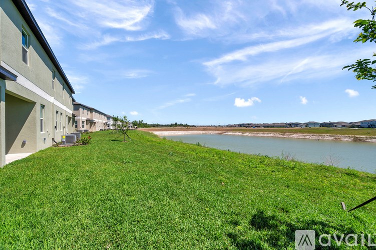 A grassy area in front of a building with a river in the background.